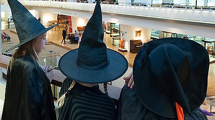 Drei als Hexen verkleidete Kinder schauen in den Ausstellungsraum des Musikinstrumenten-Museums