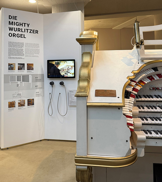 Wurlitzer-Station Spieltisch der Mighty-Wurlitzer-Orgel mit Infotafeln und Hörstation im Hintergrund