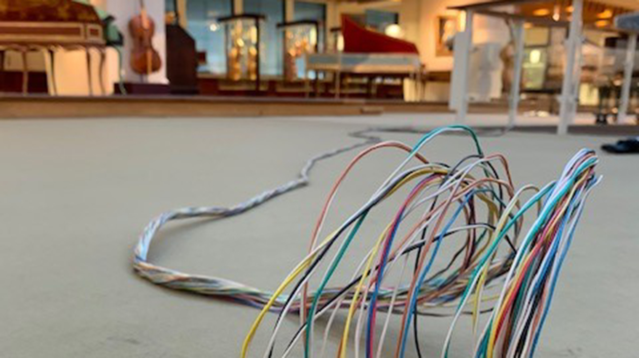 Kabel der Wurlitzer. Foto: Anne-Katrin Breitenborn Kablestränge auf einem Teppich, im Hintergrund Musikinstrumente