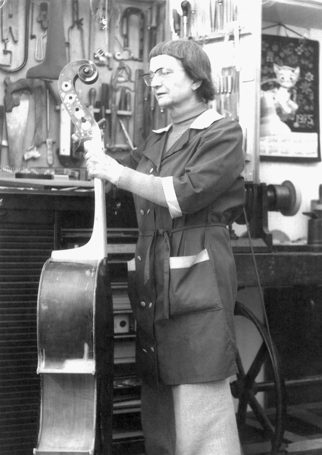 A women (Olga Adelmann) restoring a big cello like instrument.