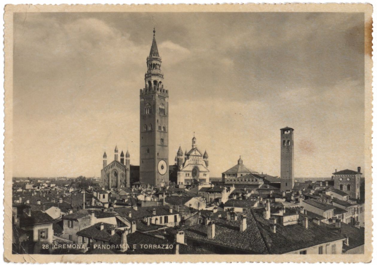 pictureside of a cpostcard schowing the view over the roofs of some houses in the middle a tower over shadows stands out in the sky. 