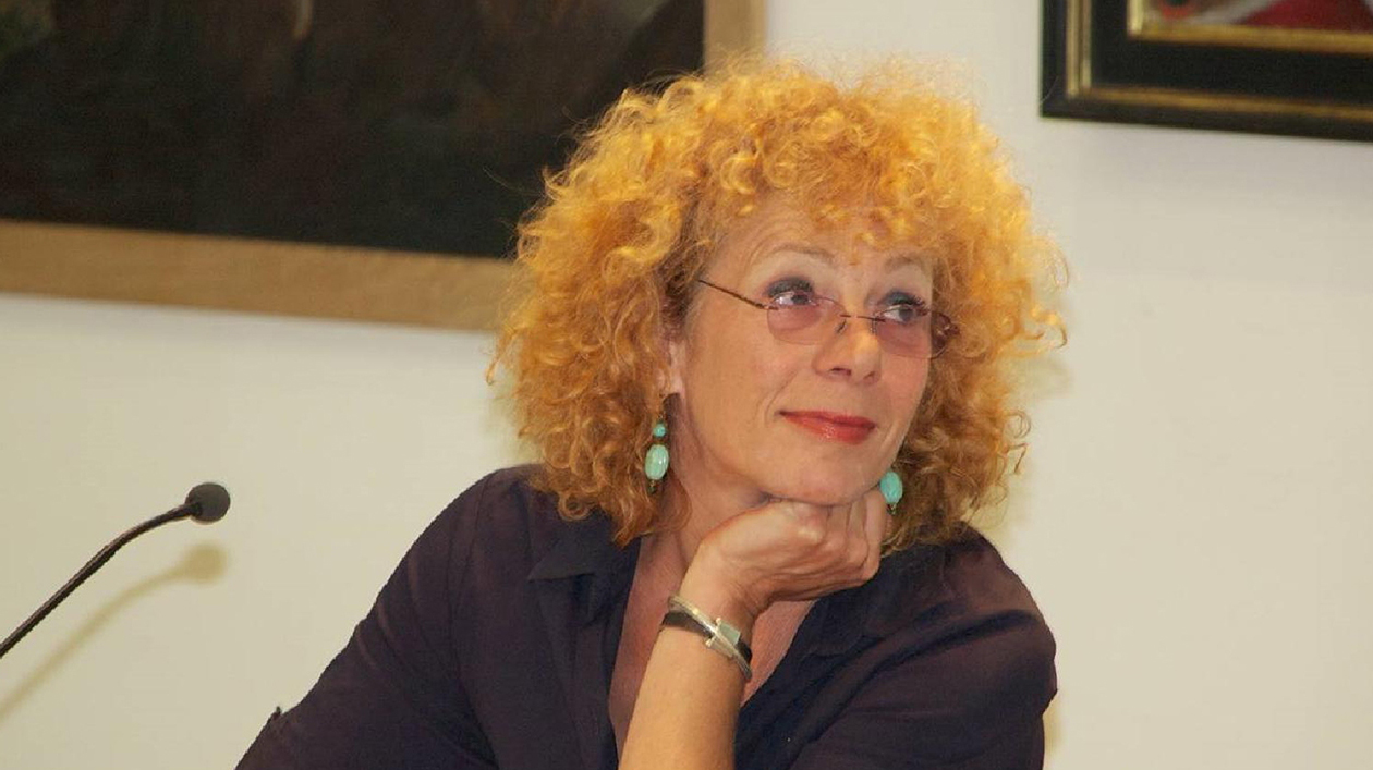 Nina Hoger. Foto: Ruth Hoffmann Eine Frau mit roten Locken sitzt vor einem Mikrofon und blickt zur Seite.